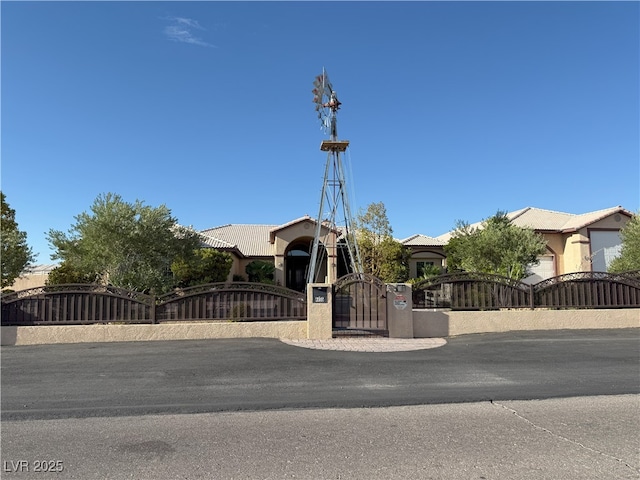 4455 W Ford Ave, Las Vegas, NV 89139 - view of property hidden behind natural elements featuring a gate, a fenced front yard, a tiled roof, and stucco siding
