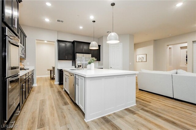 2450 Amatrice St, Henderson, NV 89044 - kitchen with light countertops, light wood finished floors, an island with sink, recessed lighting, and appliances with stainless steel finishes
