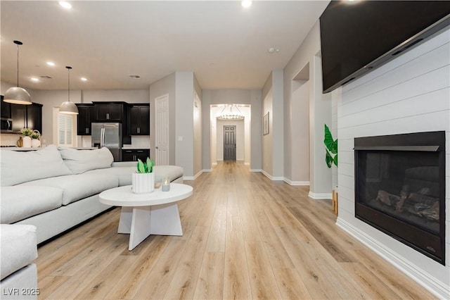 2450 Amatrice St, Henderson, NV 89044 - living area with light wood-type flooring, baseboards, recessed lighting, a chandelier, and a glass covered fireplace