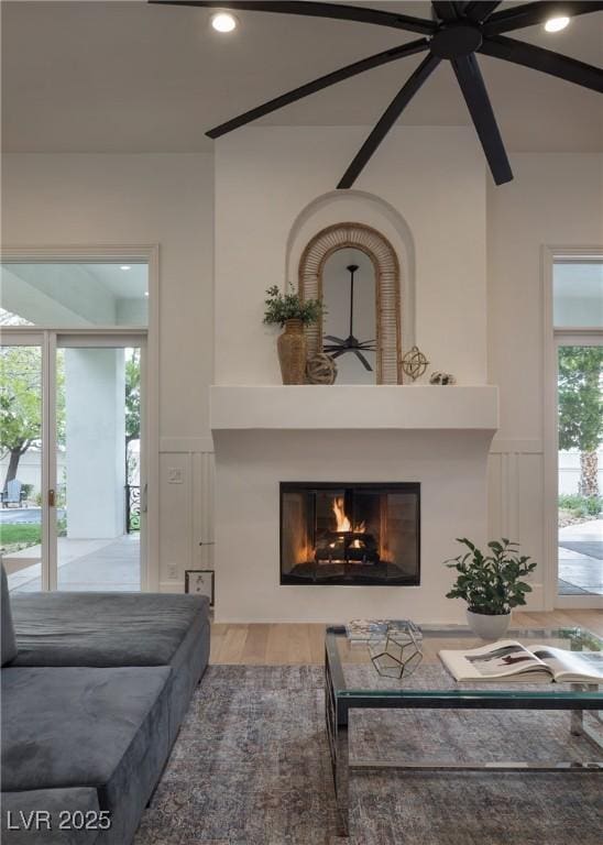 1610 Brock Ct, Las Vegas, NV 89117 - living room featuring a ceiling fan, a glass covered fireplace, a decorative wall, wainscoting, and wood finished floors