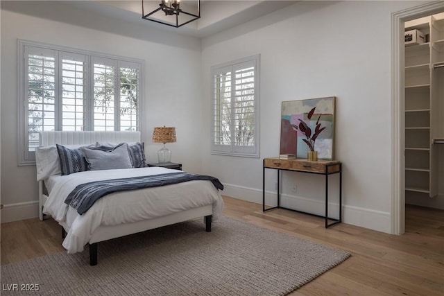 1610 Brock Ct, Las Vegas, NV 89117 - bedroom featuring a walk in closet, a chandelier, multiple windows, and light wood finished floors
