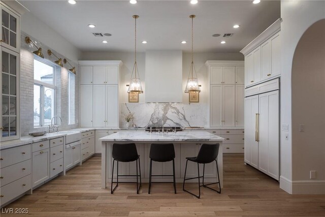 1610 Brock Ct, Las Vegas, NV 89117 - kitchen with paneled built in refrigerator, a sink, arched walkways, a center island, and white cabinetry