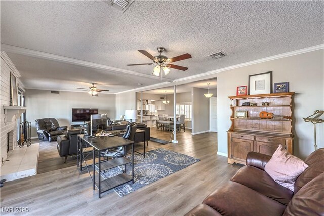 1157 Morning Sun Way, Las Vegas, NV 89110 - living room featuring a ceiling fan, crown molding, a textured ceiling, wood finished floors, and a brick fireplace