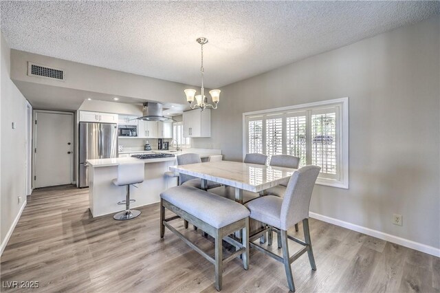 1157 Morning Sun Way, Las Vegas, NV 89110 - dining area with light wood-style floors, a chandelier, a textured ceiling, and baseboards