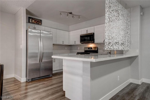 7905 Idledale Ct Unit 102, Las Vegas, NV 89145 - kitchen featuring stainless steel appliances, baseboards, dark wood-style floors, light countertops, and white cabinetry