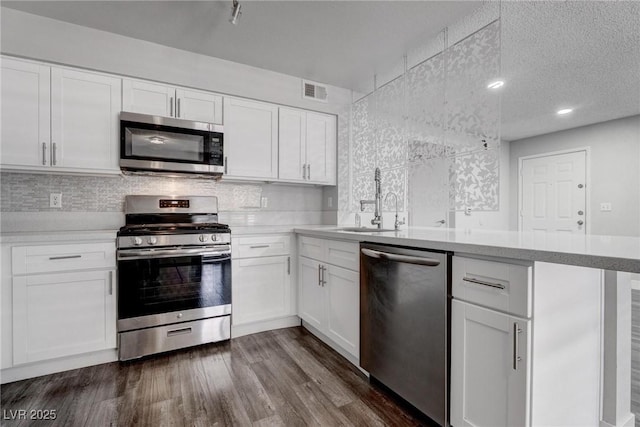 7905 Idledale Ct Unit 102, Las Vegas, NV 89145 - kitchen with stainless steel appliances, a peninsula, a sink, white cabinets, and a textured ceiling