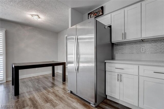 7905 Idledale Ct Unit 102, Las Vegas, NV 89145 - kitchen featuring freestanding refrigerator, decorative backsplash, a textured ceiling, wood finished floors, and light countertops