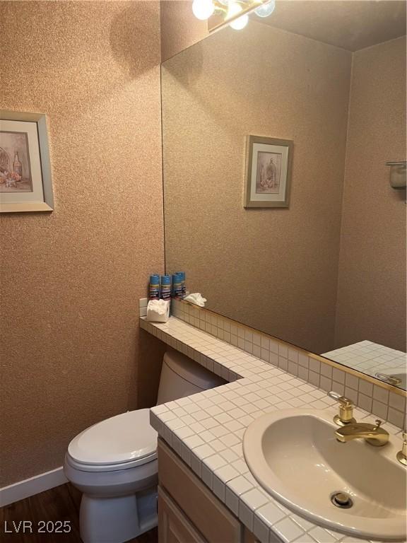 3394 Brookfield Dr, Las Vegas, NV 89120 - half bath featuring vanity, toilet, decorative backsplash, and wood finished floors