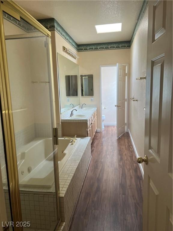 3394 Brookfield Dr, Las Vegas, NV 89120 - full bath featuring wood finished floors, a jetted tub, toilet, double vanity, and a shower with shower door