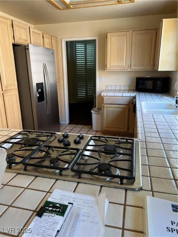 3394 Brookfield Dr, Las Vegas, NV 89120 - kitchen with tile counters, stainless steel fridge, black microwave, light brown cabinets, and light tile patterned floors