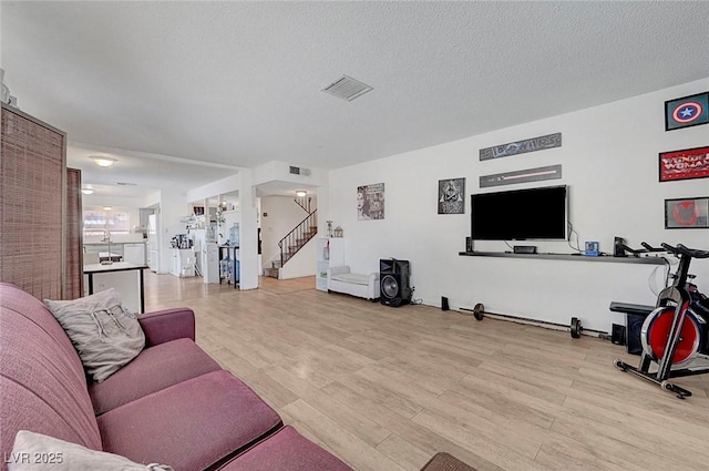 3018 Burnham Ave, Las Vegas, NV 89169 - living room featuring stairs, light wood-type flooring, and a textured ceiling