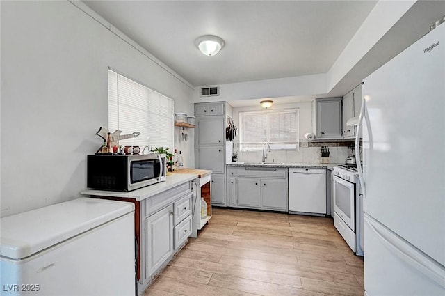 3018 Burnham Ave, Las Vegas, NV 89169 - kitchen featuring white appliances, a sink, light wood-type flooring, light countertops, and gray cabinetry
