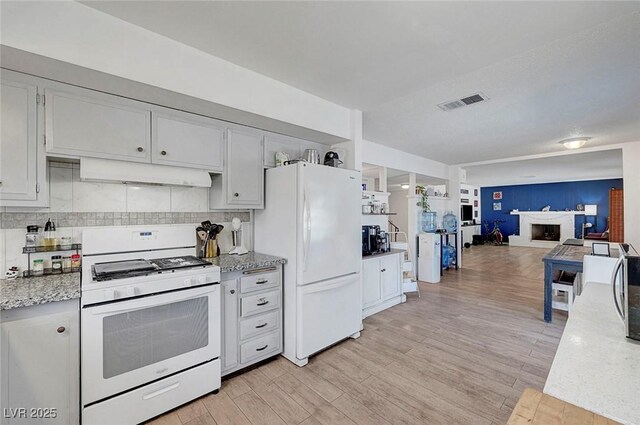 3018 Burnham Ave, Las Vegas, NV 89169 - kitchen featuring white appliances, under cabinet range hood, light wood-style floors, open floor plan, and backsplash