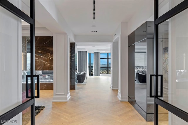 corridor featuring baseboards and decorative columns