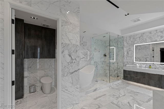 full bath with marble finish flooring, tile walls, a freestanding tub, a shower stall, and double vanity