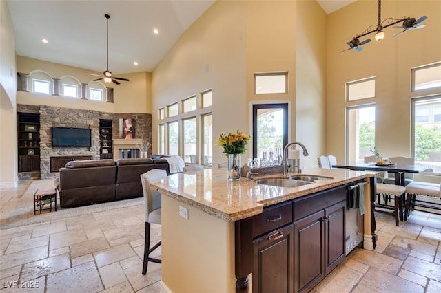 9749 Glistening Brook Ct, Las Vegas, NV 89149 - kitchen featuring a sink, ceiling fan, a fireplace, stone tile floors, and a high ceiling