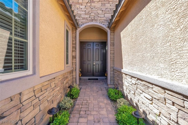entrance to property featuring stucco siding and stone siding