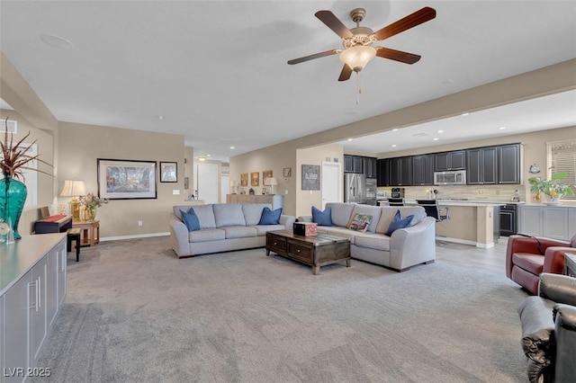 living room featuring light colored carpet, a ceiling fan, baseboards, and recessed lighting