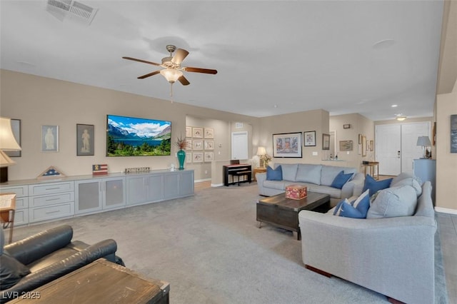 living area featuring a ceiling fan, baseboards, and light carpet