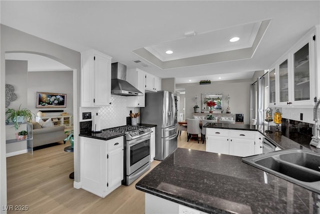 4617 Mancilla St, Las Vegas, NV 89130 - kitchen featuring stainless steel appliances, wall chimney exhaust hood, a raised ceiling, white cabinets, and light wood-type flooring