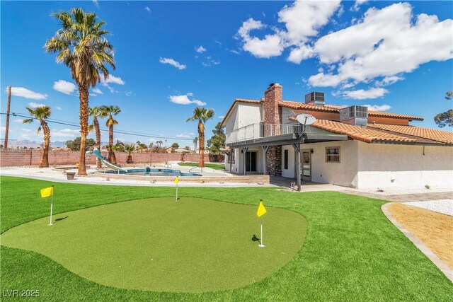 4061 W Eldorado Ln, Las Vegas, NV 89139 - rear view of property with an area to practice putting, a patio area, a balcony, stucco siding, and a chimney