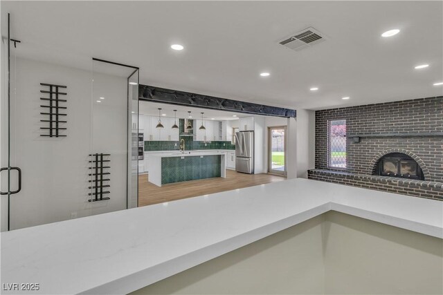 4061 W Eldorado Ln, Las Vegas, NV 89139 - bathroom featuring decorative backsplash, recessed lighting, wood finished floors, a brick fireplace, and vanity