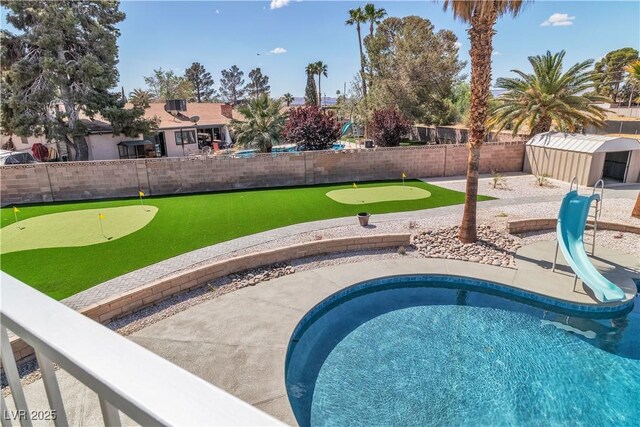 4061 W Eldorado Ln, Las Vegas, NV 89139 - view of pool featuring an area to practice putting, a fenced backyard, a shed, and an outbuilding