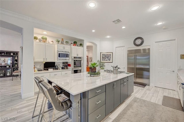 729 Sir James Bridge Way, Las Vegas, NV 89145 - kitchen with built in appliances, white cabinetry, arched walkways, ornamental molding, and light wood-type flooring