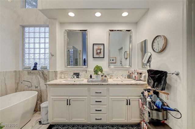 729 Sir James Bridge Way, Las Vegas, NV 89145 - bathroom featuring double vanity, a freestanding bath, wainscoting, and tile walls