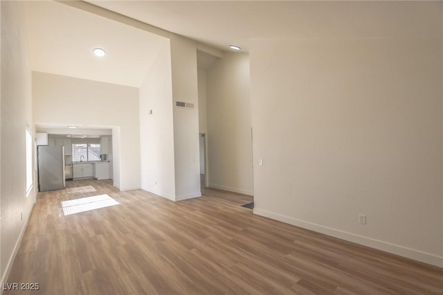 6842 Greengrove Dr, Las Vegas, NV 89103 - unfurnished living room with light wood-style floors, baseboards, recessed lighting, and high vaulted ceiling