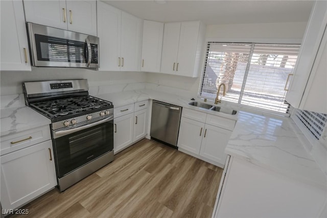 6842 Greengrove Dr, Las Vegas, NV 89103 - kitchen with appliances with stainless steel finishes, a sink, light wood-style flooring, and white cabinetry