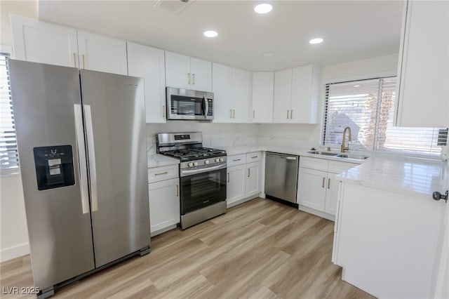6842 Greengrove Dr, Las Vegas, NV 89103 - kitchen featuring stainless steel appliances, a sink, white cabinetry, light wood-type flooring, and light stone countertops