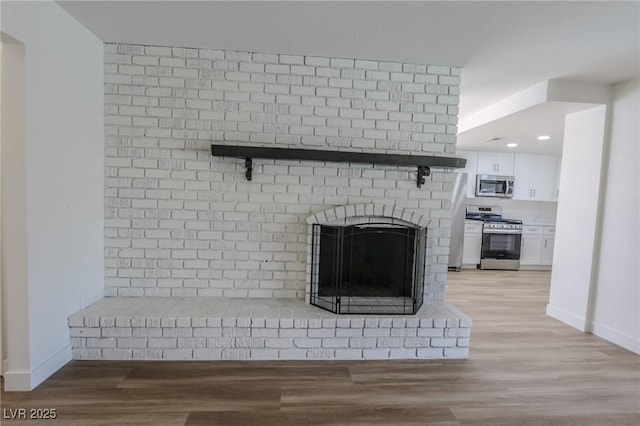 6842 Greengrove Dr, Las Vegas, NV 89103 - detailed view of stainless steel appliances, wood finished floors, baseboards, a brick fireplace, and recessed lighting