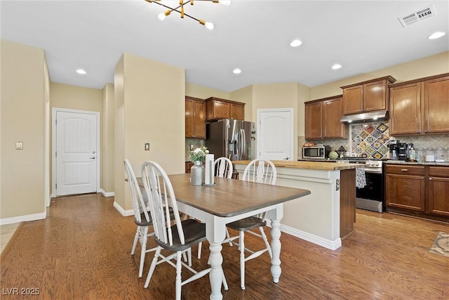 6049 Paddleboat St, North Las Vegas, NV 89031 - kitchen with stainless steel appliances, under cabinet range hood, wood finished floors, decorative backsplash, and recessed lighting
