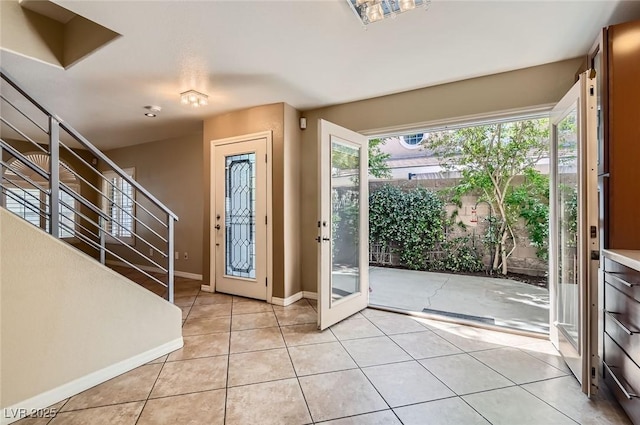 entryway featuring light tile patterned floors, stairway, and baseboards