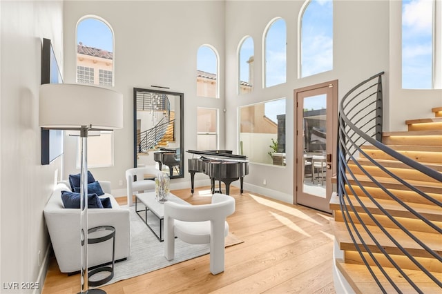 11453 Glowing Sunset Ln, Las Vegas, NV 89135 - living room featuring healthy amount of natural light, light wood finished floors, a towering ceiling, stairs, and baseboards