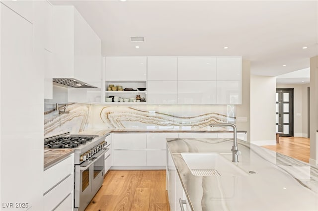 11453 Glowing Sunset Ln, Las Vegas, NV 89135 - kitchen with range with two ovens, modern cabinets, a sink, premium range hood, and white cabinetry
