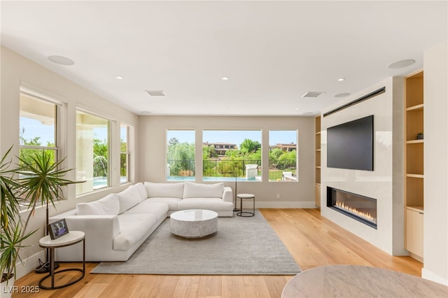 11453 Glowing Sunset Ln, Las Vegas, NV 89135 - living area with healthy amount of natural light, light wood finished floors, a glass covered fireplace, built in shelves, and recessed lighting
