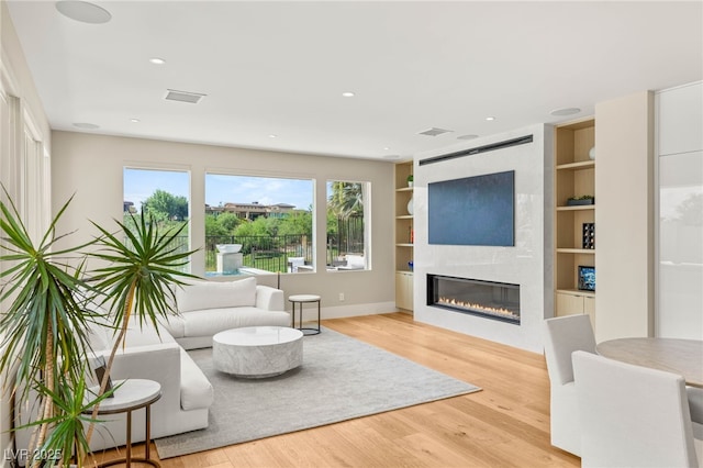 11453 Glowing Sunset Ln, Las Vegas, NV 89135 - living area with plenty of natural light, a large fireplace, wood finished floors, built in shelves, and recessed lighting