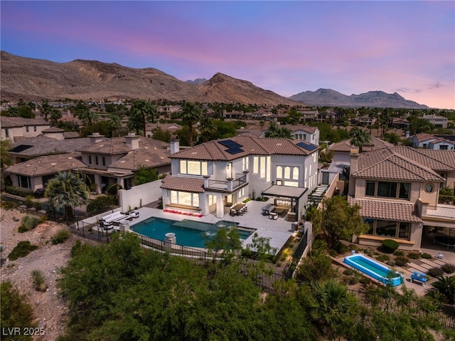 11453 Glowing Sunset Ln, Las Vegas, NV 89135 - rear view of house featuring a balcony, a fenced backyard, a residential view, solar panels, and a mountain view