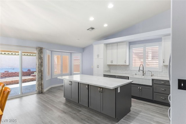 5441 Rose Hills St, Las Vegas, NV 89149 - kitchen featuring a sink, backsplash, a kitchen island, light wood-style floors, and white cabinetry