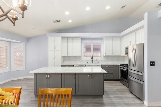 5441 Rose Hills St, Las Vegas, NV 89149 - kitchen featuring stainless steel appliances, a center island, lofted ceiling, decorative backsplash, and light wood-style flooring