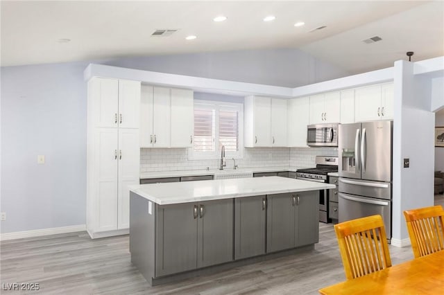 5441 Rose Hills St, Las Vegas, NV 89149 - kitchen featuring stainless steel appliances, lofted ceiling, a center island, white cabinetry, and light wood finished floors