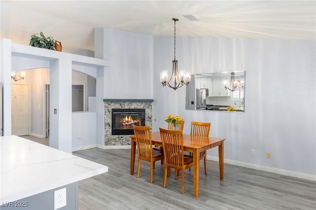 5441 Rose Hills St, Las Vegas, NV 89149 - dining room featuring a chandelier, light wood-type flooring, a glass covered fireplace, baseboards, and vaulted ceiling