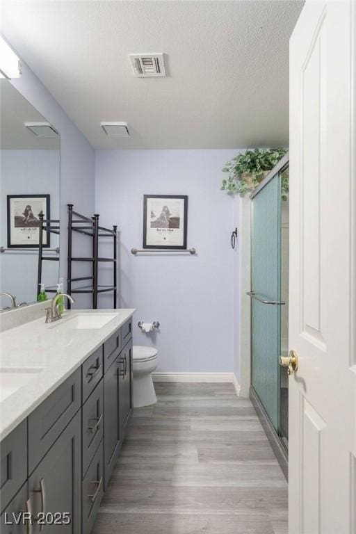 5441 Rose Hills St, Las Vegas, NV 89149 - bathroom with baseboards, toilet, double vanity, a shower stall, and wood finished floors