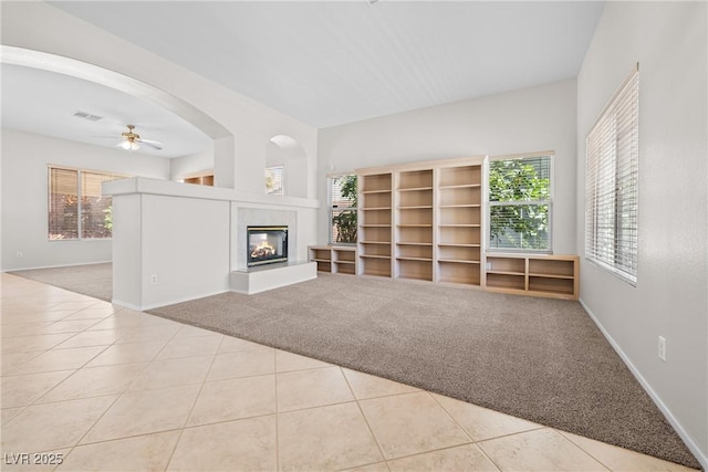 9282 W Viking Rd, Las Vegas, NV 89147 - unfurnished living room with carpet floors, plenty of natural light, a glass covered fireplace, and a ceiling fan