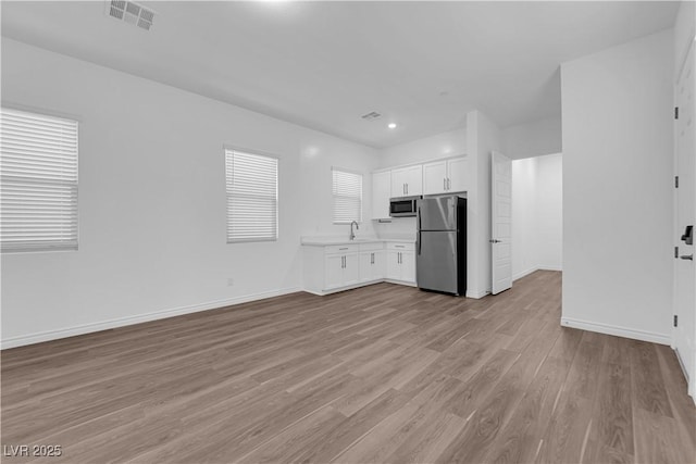 720 Webber Park St, Henderson, NV 89011 - kitchen featuring stainless steel appliances, light countertops, light wood-style flooring, white cabinetry, and baseboards