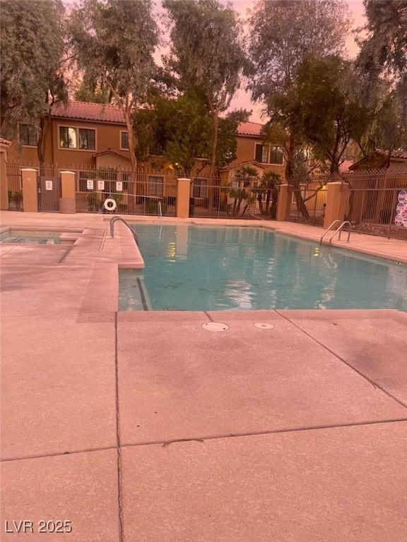 2151 Hussium Hills St Unit 207, Las Vegas, NV 89108 - pool at dusk featuring a community pool, fence, and a patio
