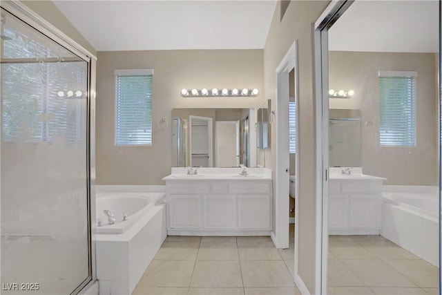 bathroom featuring tile patterned flooring, a shower stall, a bath, and two vanities