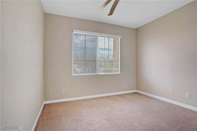 carpeted spare room with a ceiling fan and baseboards